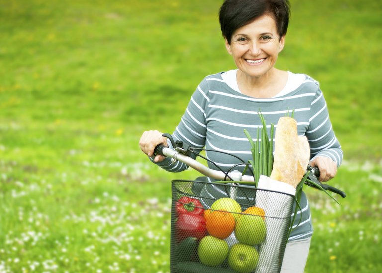 [Translate to Germany - deutsch:] Woman on a bike with healthy food in the basket